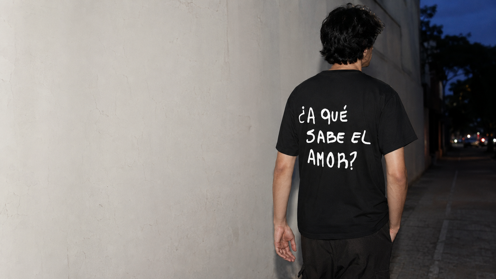 Persona caminando con una remera negra personalizada con una frase en la espalda.